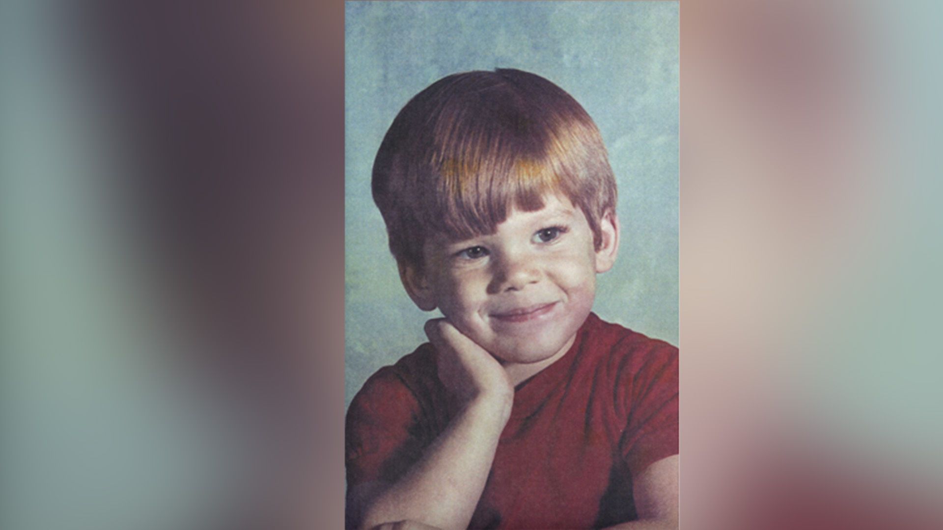 Michael C. Hall de niño con una camisa roja mirando hacia un lado