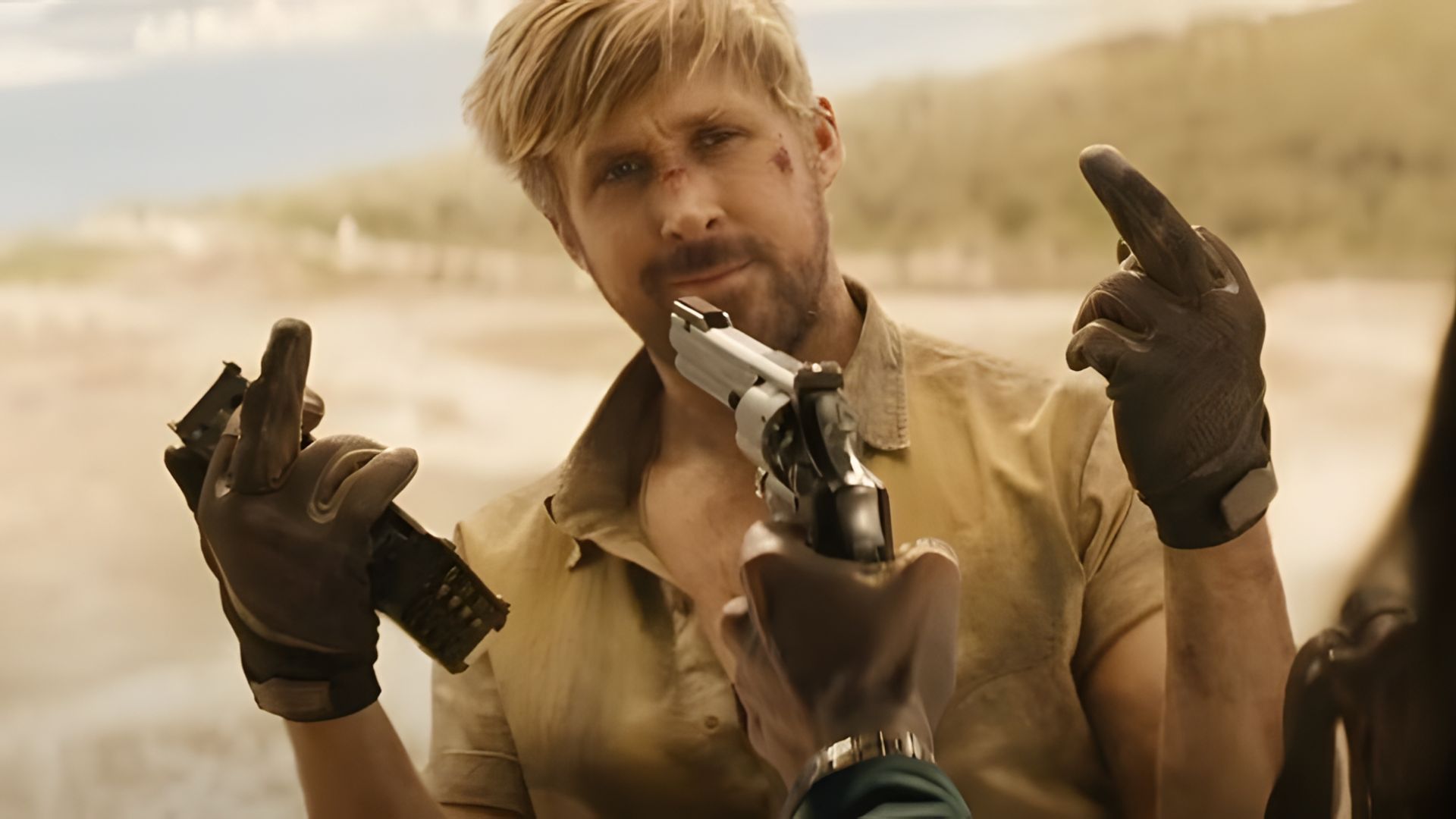Ryan Gosling con la cara magullada hace un gesto obsceno mientras le apuntan con una pistola a la cara