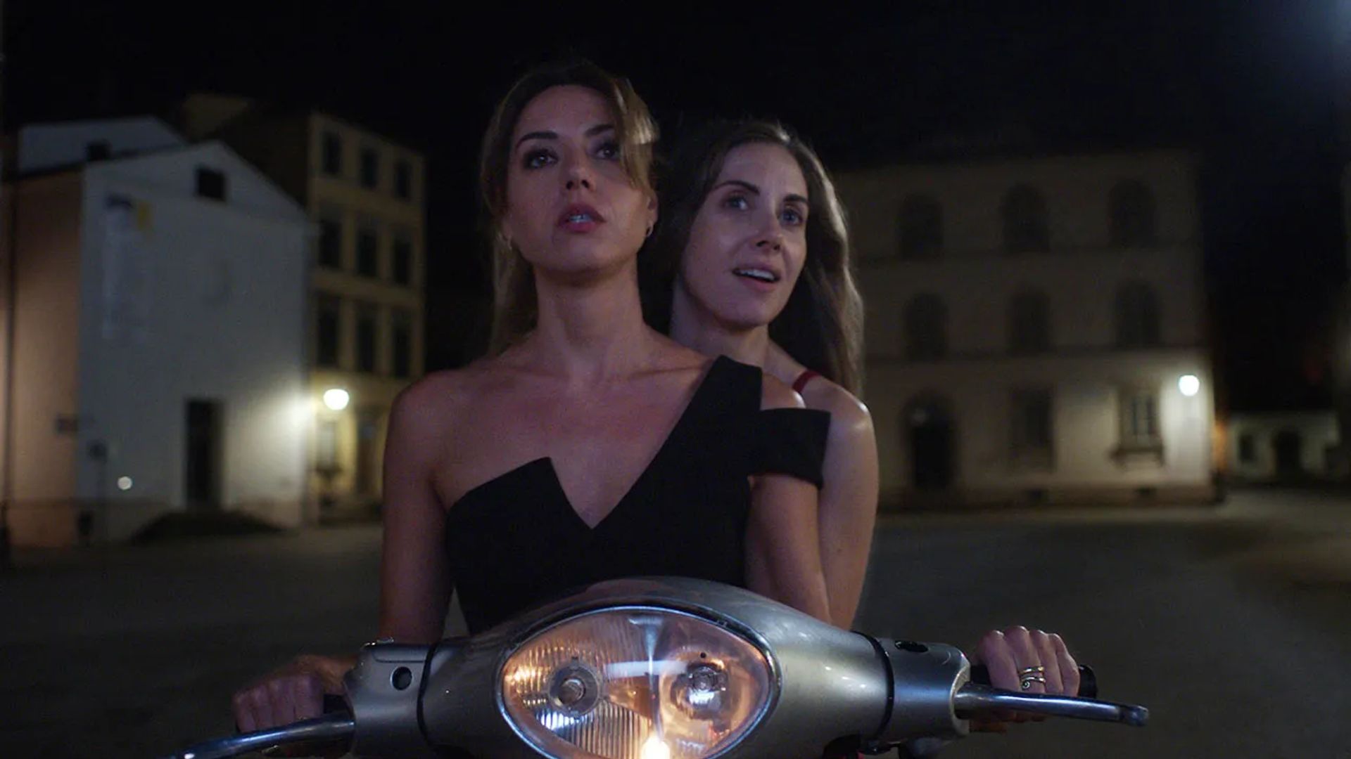 Alison Brie y Aubrey Plaza montan una motocicleta en la oscuridad, una escena de "Spin Me Round"