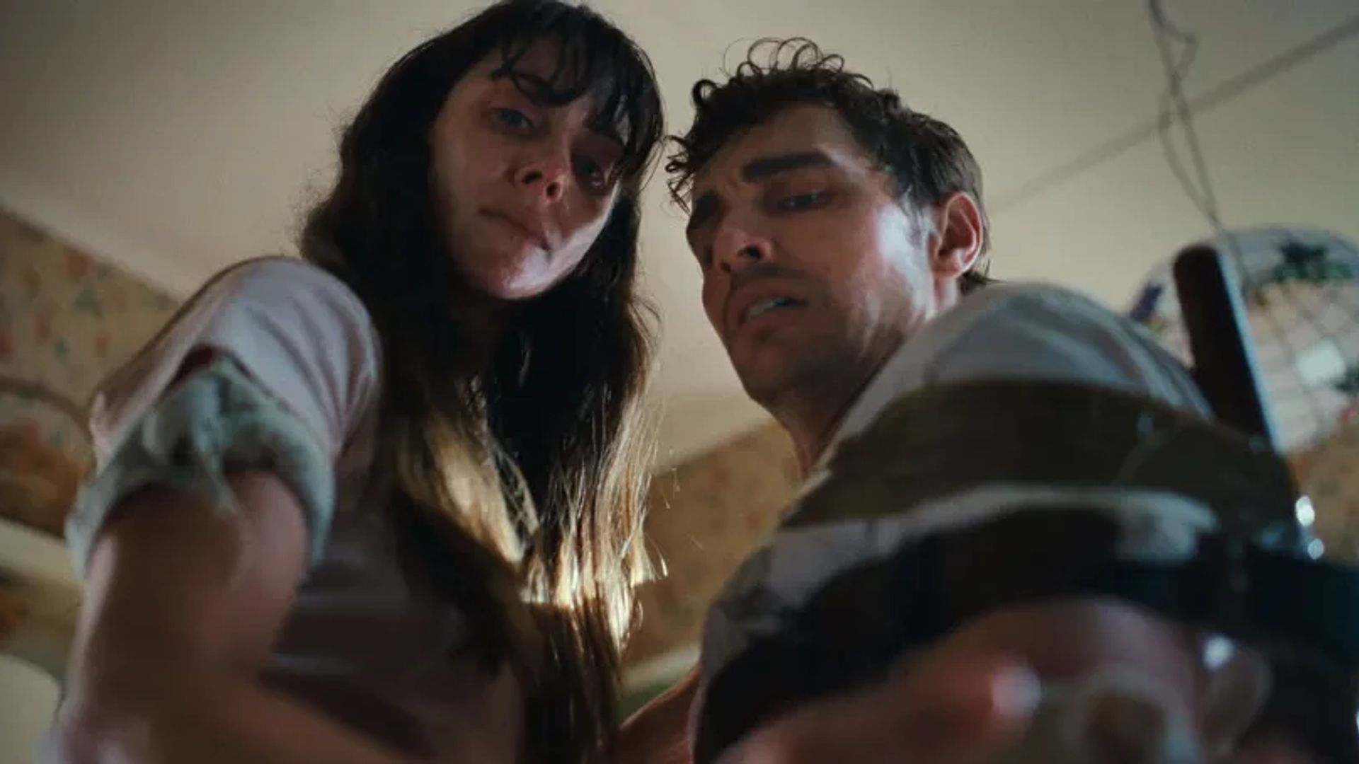 Alison Brie y Dave Franco miran a la cámara con expresiones preocupadas, tomados desde un ángulo bajo