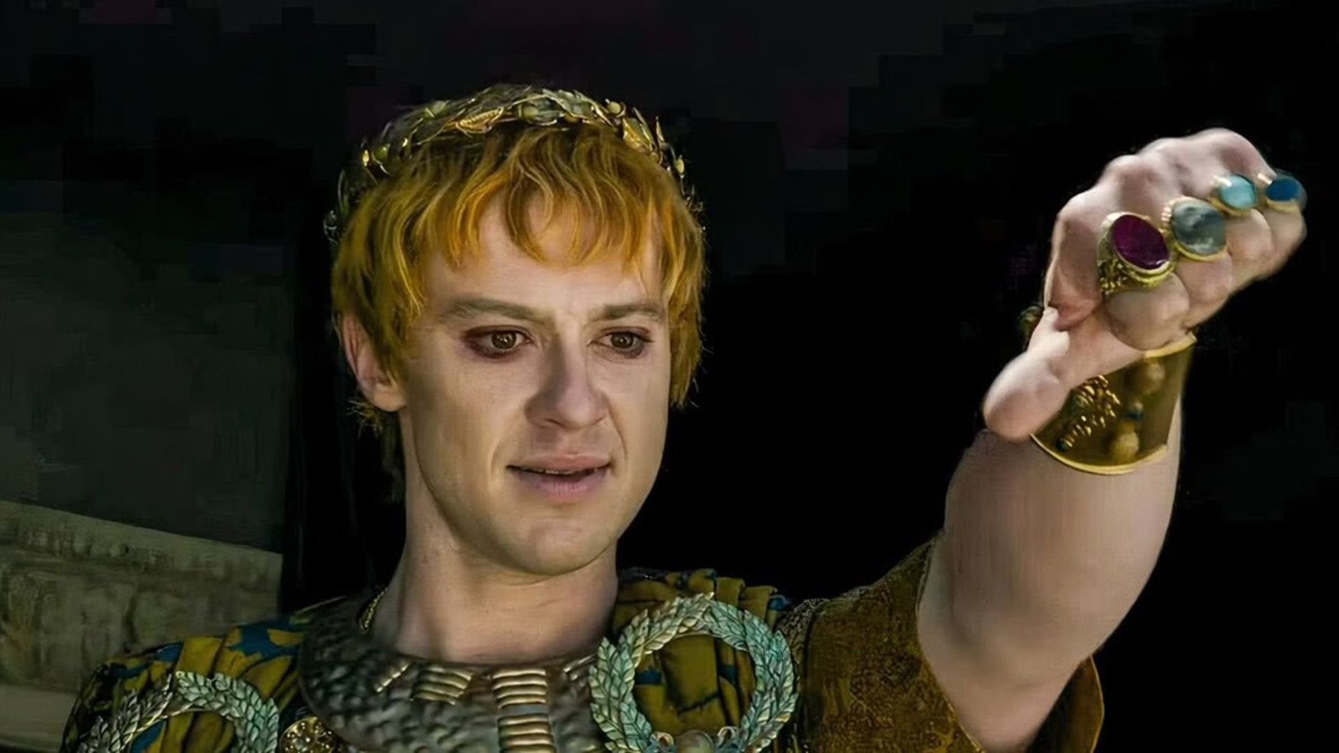Joseph Quinn con maquillaje y vestuario de emperador romano mostrando un gesto de pulgar hacia abajo