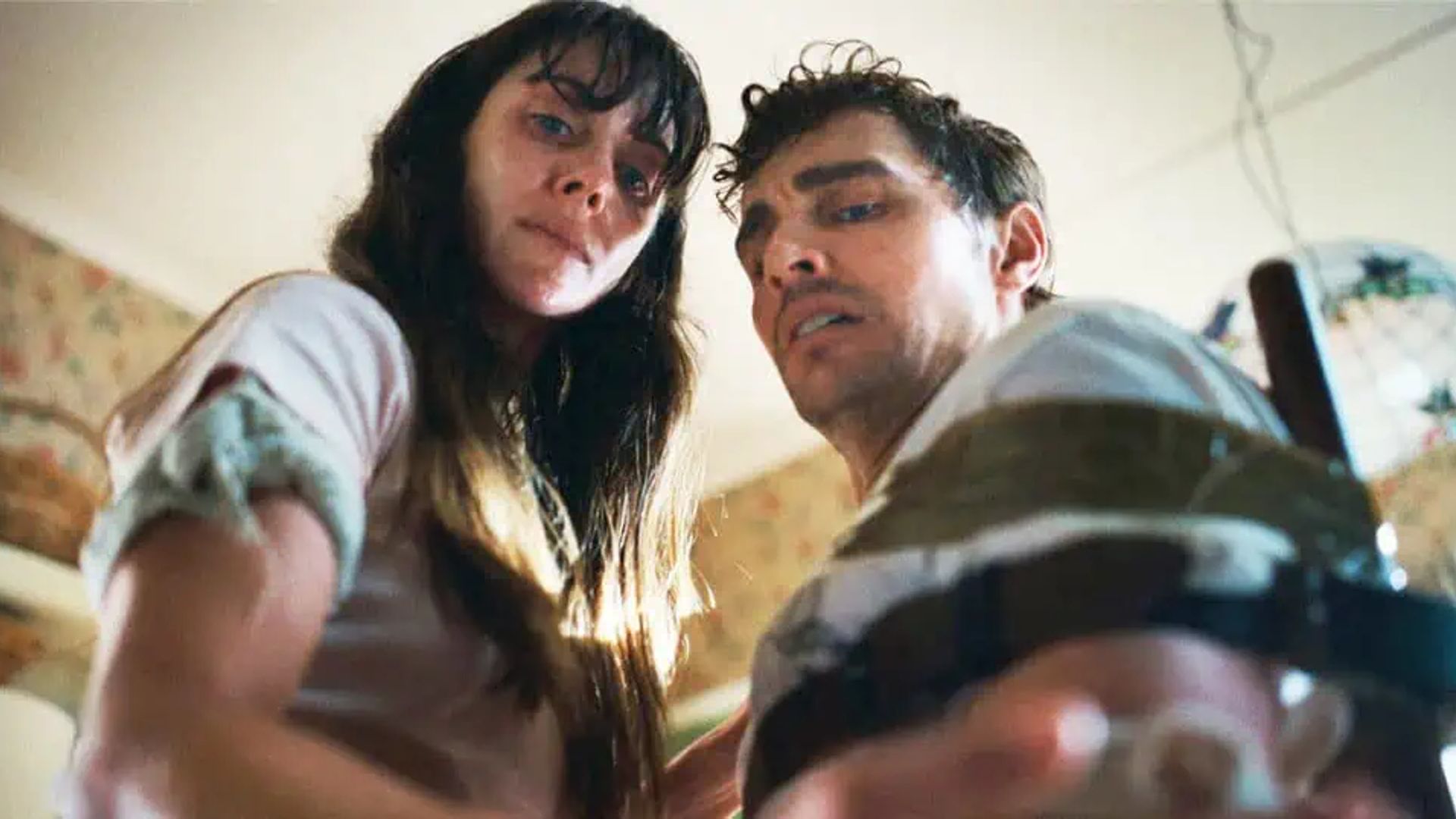 Dave Franco y Alison Brie miran hacia abajo a la cámara con expresiones de cansancio en sus rostros