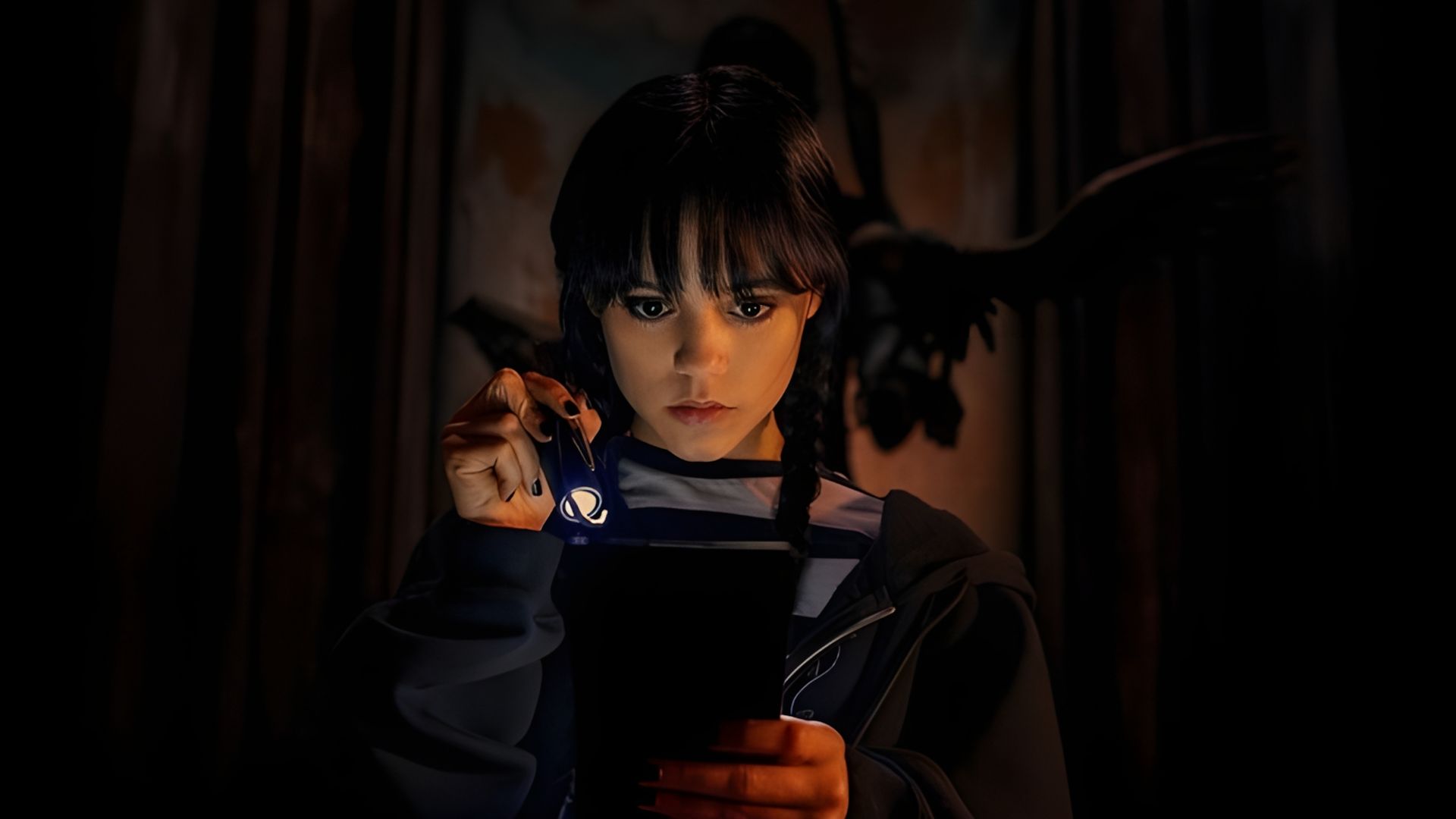 Jenna Ortega como Wednesday Addams sosteniendo una linterna y mirando un libro