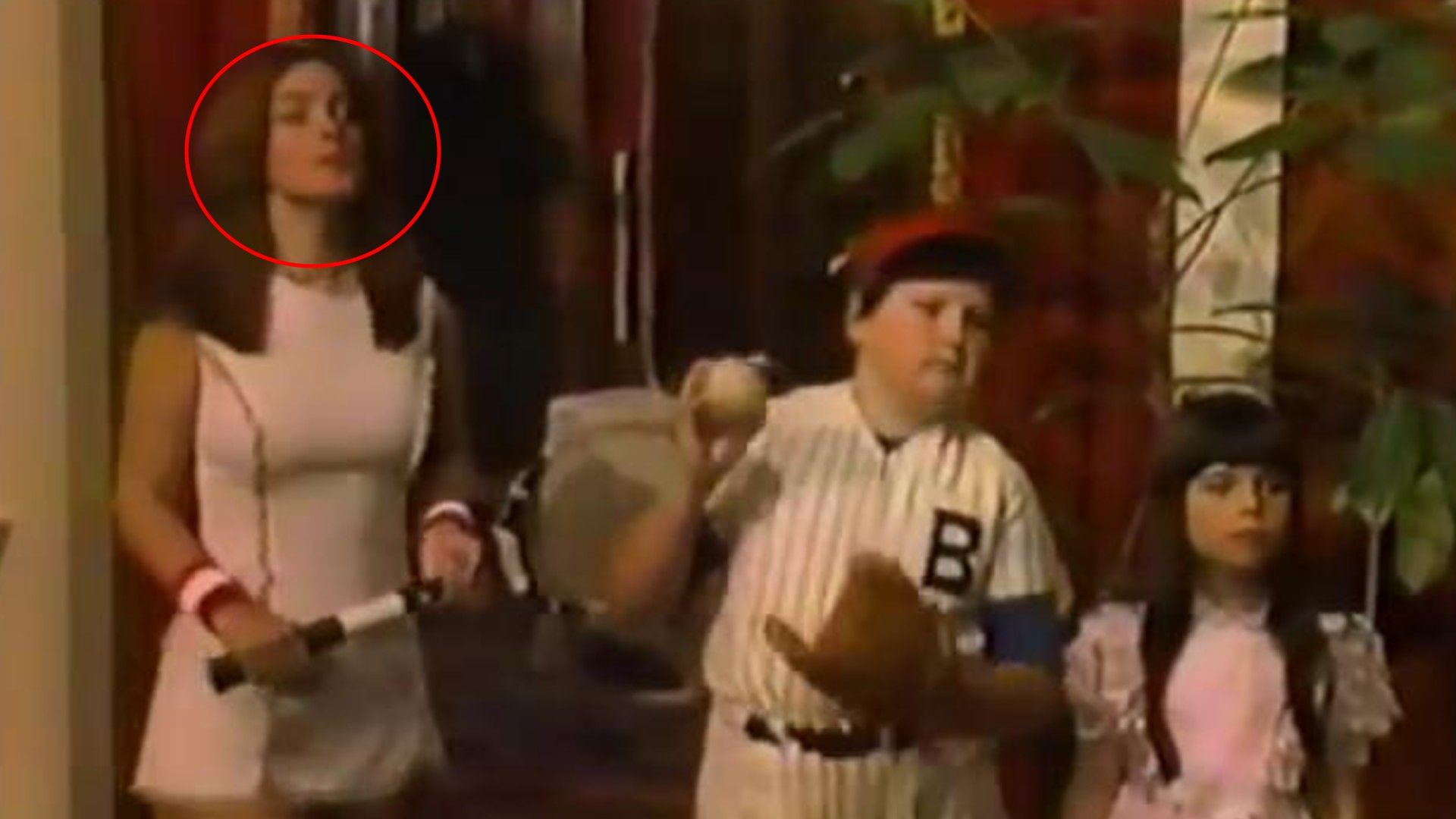 Mujer en traje de tenis blanco con raqueta y dos niños con ropa de béisbol y rosa en interiores