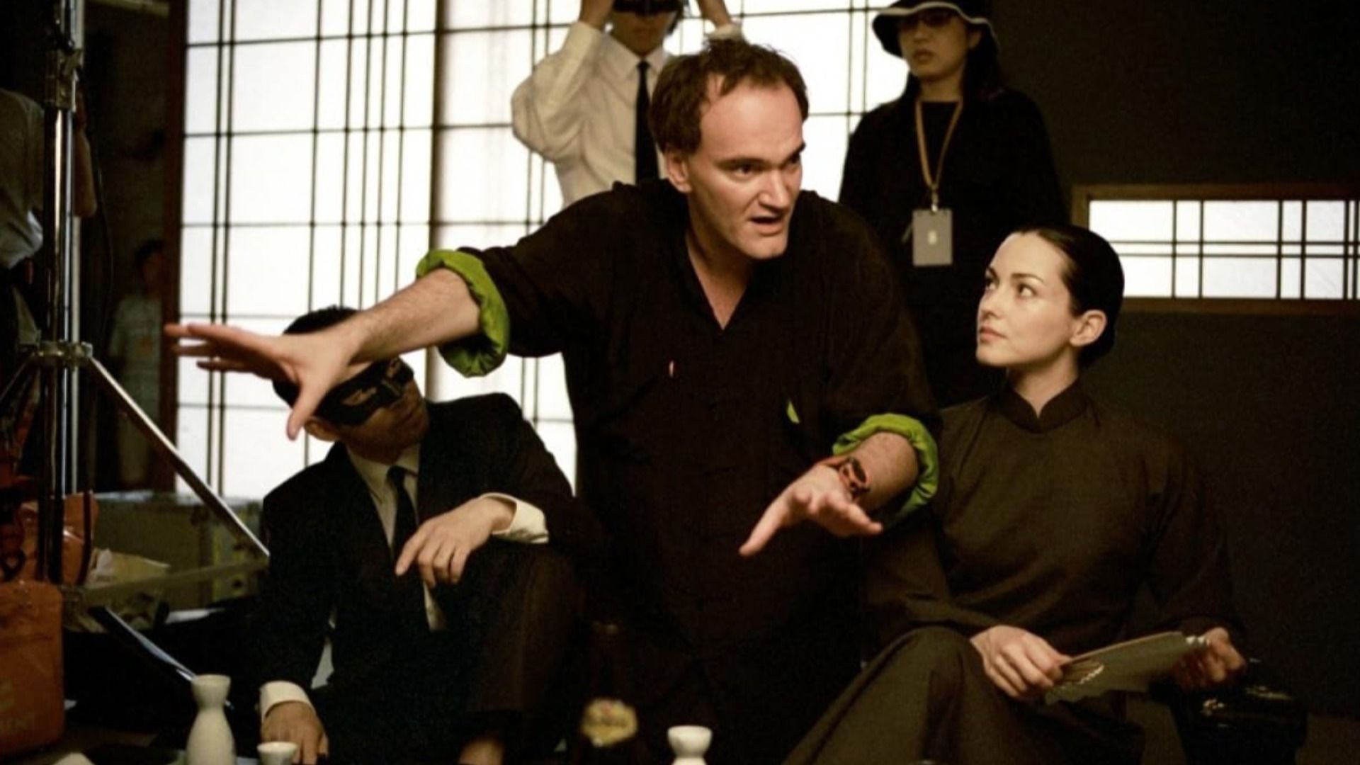 Director Quentin Tarantino con ropa negra dando indicaciones a personas vestidas de negro