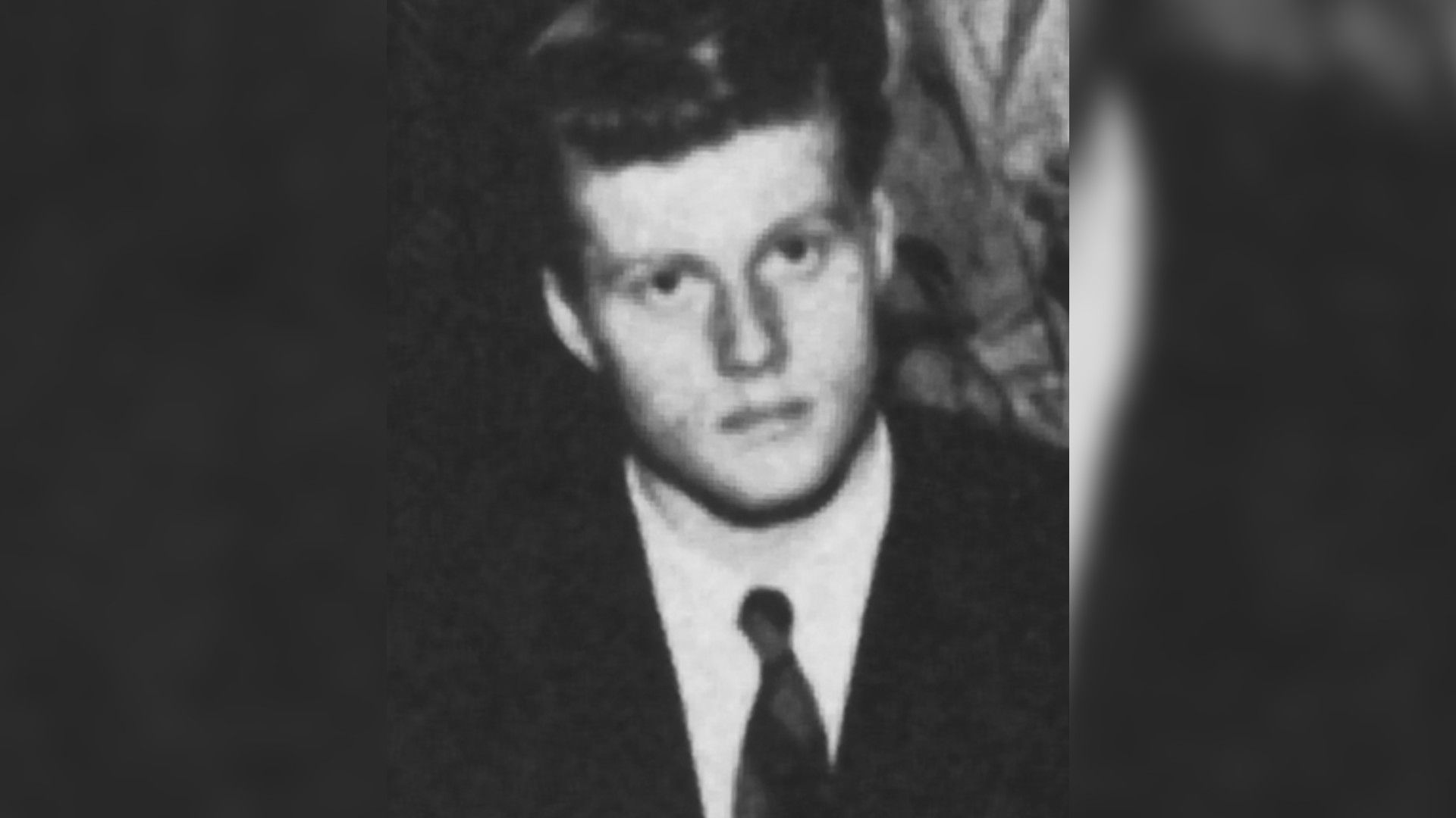Un retrato en blanco y negro del joven Robert Redford con traje y corbata, mirando directamente a la cámara.