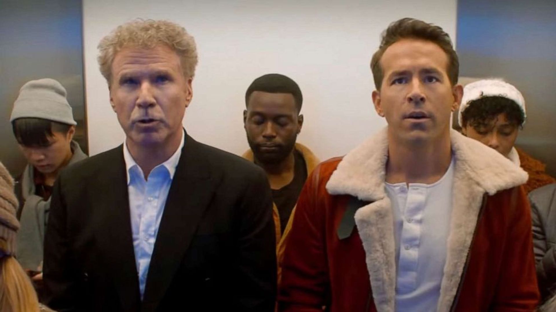 Ryan Reynolds y Will Ferrell montando en un ascensor y mirando al mismo punto