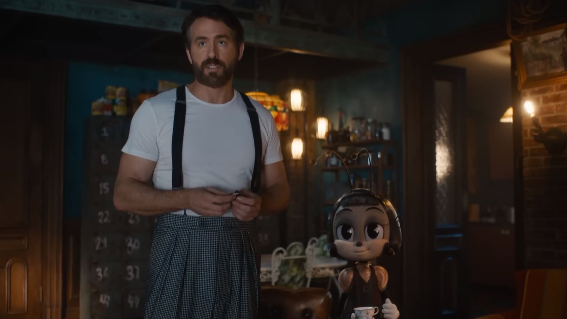 Ryan Reynolds con camiseta blanca y tirantes junto a un personaje de hormiga de dibujos animados sosteniendo una taza de té