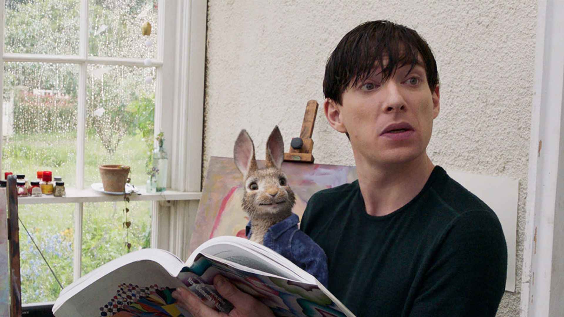 Domhnall Gleeson sentado leyendo un periódico con un conejo de juguete en su regazo