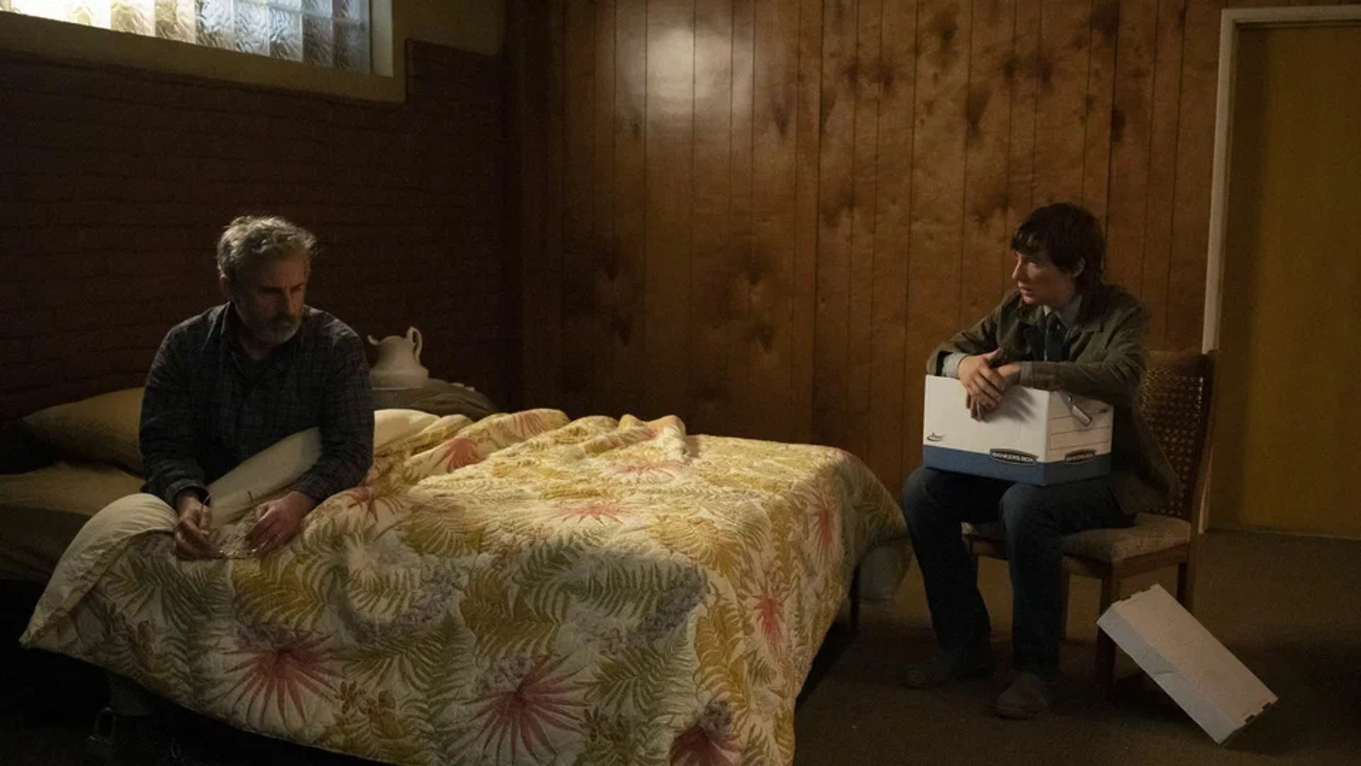 Steve Carell acostado en una cama con Domhnall Gleeson sentado en una silla frente a él