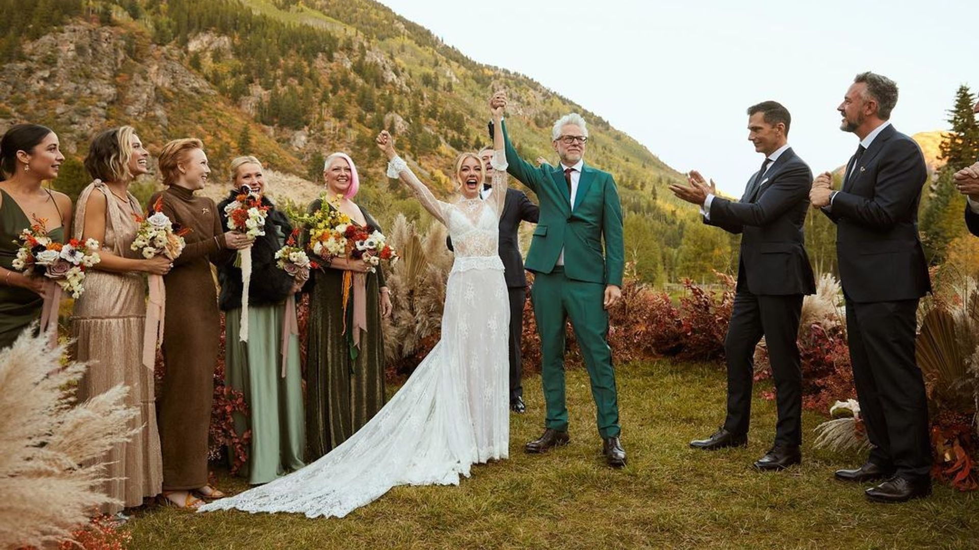 Jennifer Holland y James Gunn en traje de boda contra un telón de fondo de montañas pintorescas