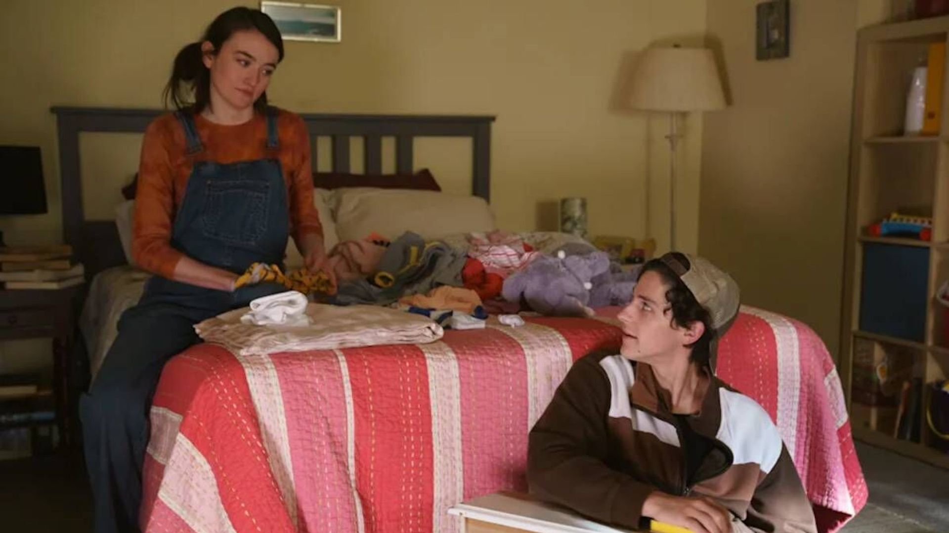 Sarah Pidgeon y Owen Painter sentados en una cama, una escena de la serie "The Sex Lives of College Girls"